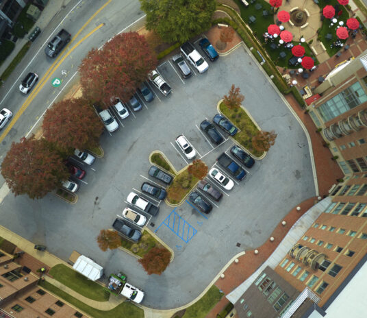 Aerial view of many colorful cars parked on parking lot on apartment building backyard. Place for vehicles in front of residential condo.